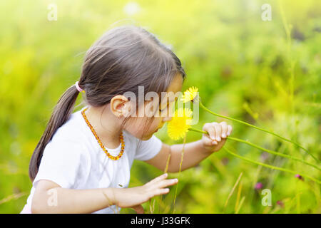 little girl in the forest smells wonderful flowers and enjoy the tranquility of a summer day Stock Photo