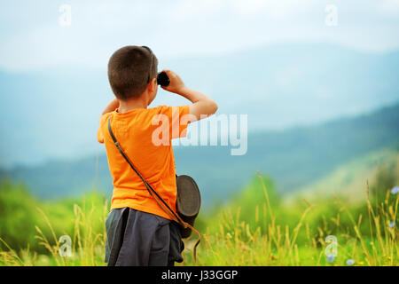 Little boy looking through binoculars outdoor. He is lost. Trying to find a way home Stock Photo