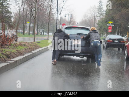 Two women pushing a car in the rain. Stock Photo