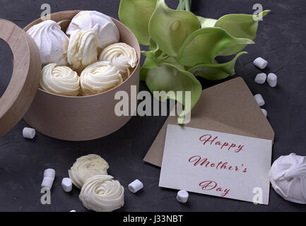 bouquet of green yellow callas with marshmallows in a wooden round box and envelope with lettering Happy Mother's Day on gray concrete background Stock Photo