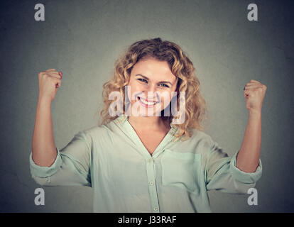 Closeup portrait happy successful woman pumping fists celebrating success isolated on grey wall background. Positive human emotion facial expression Stock Photo