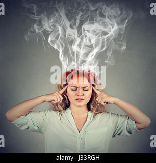 Woman thinks very intensely having headache isolated on gray wall background Stock Photo
