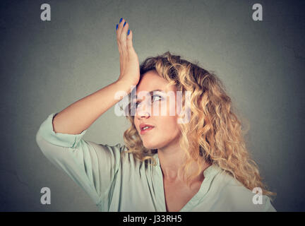Regrets wrong doing. Closeup portrait silly young woman, slapping hand on head having duh moment isolated on gray background. Negative human emotion f Stock Photo