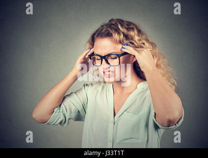 Closeup portrait sad young woman in glasses with worried stressed face expression isolated on gray wall background. Obsessive compulsive, adhd, anxiet Stock Photo