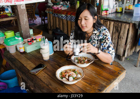 Thai woman shooting photo noodle tom yum seafood thai style before eating at local restaurant for writing blog on February 23, 2017 in Loei, Thailand Stock Photo