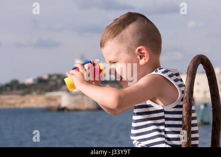 funny small boy looking into the distance through binoculars Stock Photo