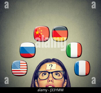 Work and travel immigration opportunity concept. Foreign language studying process. Woman with question mark and many icons of international flags abo Stock Photo