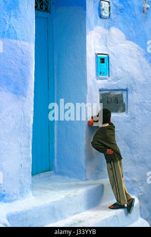 A boy plays hide and seek inside the old medina of Chefchouen. Rif mountains, Morocco. Stock Photo