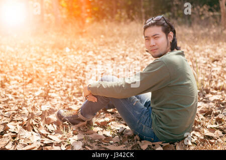 younger asian man sitting on dry leaves relaxing emotion Stock Photo