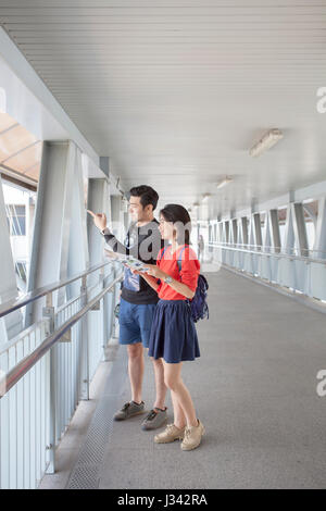 asian younger man and woman looking to traveling destination guide book  in hand Stock Photo
