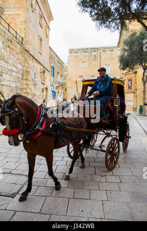 A carriage emerges from the main gate of Mdina, a fortified hilltop city in the norther region of Malta that served as the island's capital from medie Stock Photo