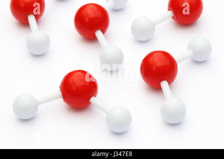 Plastic ball-and-stick models of water molecules on a white background. Water molecules consist of two hydrogen atoms connected to an oxygen atom. Stock Photo