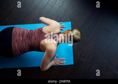 Fit young woman doing press-ups as she works out on a mat at the gym viewed from overhead with copy space in a health and fitness concept Stock Photo