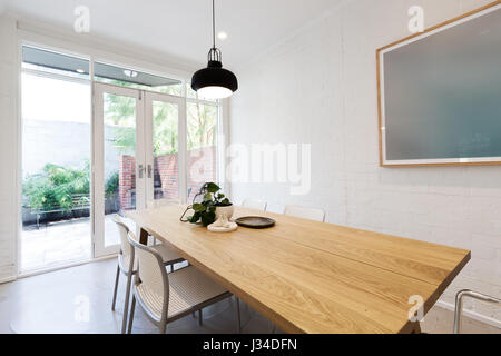 Scandi styled dining room interior with outlook to courtyard through french doors Stock Photo