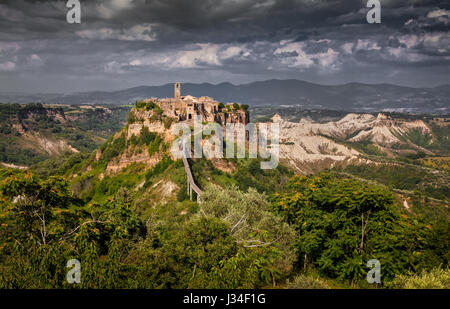 Beautiful view of famous Civita di Bagnoregio with Tiber river valley and dramatic dark cloudscape at sunset, Lazio, Italy Stock Photo