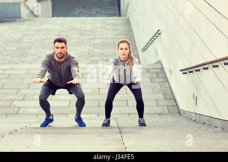 couple doing squats and exercising outdoors Stock Photo