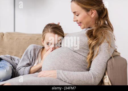 pregnant woman and girl talking to baby in belly Stock Photo