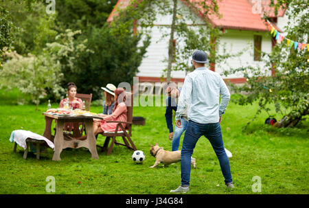 friends playing football with dog at summer garden Stock Photo