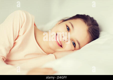 happy smiling girl lying awake in bed at home Stock Photo