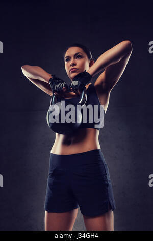 young woman flexing muscles with kettlebell in gym Stock Photo