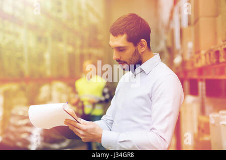 businessman writing to clipboard at warehouse Stock Photo