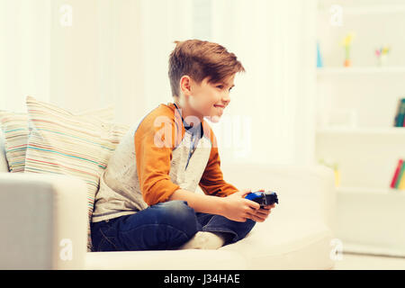 happy boy with joystick playing video game at home Stock Photo