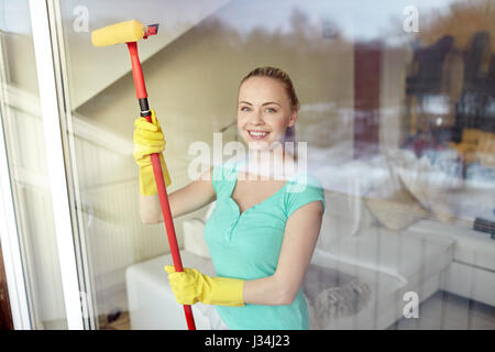 happy woman in gloves cleaning window with sponge Stock Photo