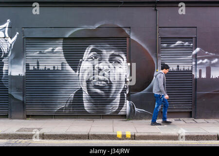 Man, motion blurred, walking past mural in Coldharbour Lane, Brixton. Stock Photo