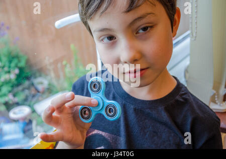 A young boy plying with a fidget spinner. Stock Photo