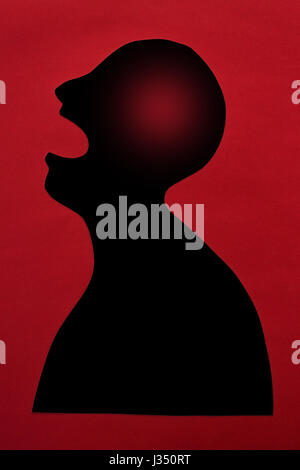 concept of human disease diagnosis and pain localization on silhouette - contour of abstract black male man with significant brain damage, opened mouth, isolated on red background, top view, flat lay. Stock Photo