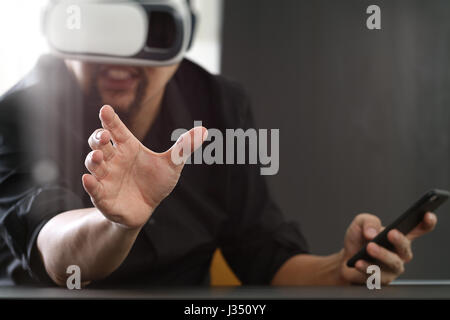businessman wearing virtual reality goggles in modern office with mobile phone using with VR headset Stock Photo