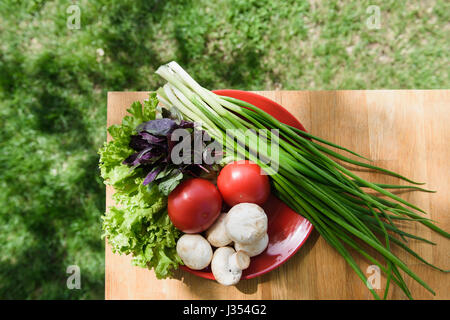 Healthy food fresh vegetables in red plate on wooden table. Stock Photo