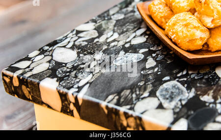 Perspective view of bread inside wooden plait on modern kitchen black and white granite countertop. Stock Photo