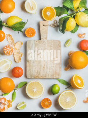 Variety of fresh citrus fruit and wooden board in center Stock Photo