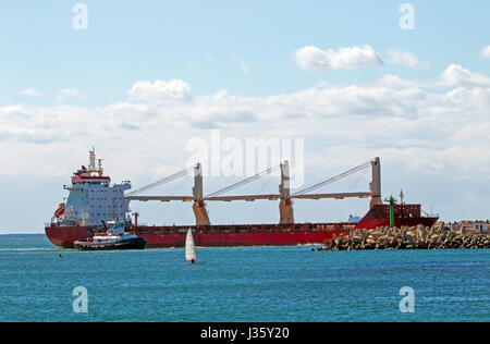 Large container vessel and tugboat entering harbor in Durban, South Africa Stock Photo
