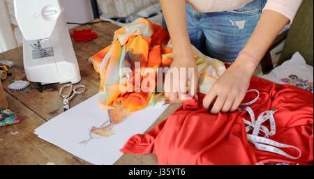 Crop faceless shot of female using sketch and choosing colorful fabric for dress. Stock Photo