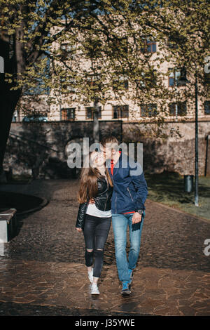 Front view of a young couple embracing and walking in the rainy street Stock Photo