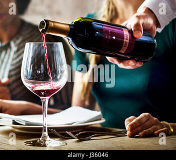 Waiter Poring Serving Red Wine to Customers in a Restaurant Stock Photo