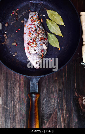 https://l450v.alamy.com/450v/j3640j/fish-carp-in-spices-on-a-black-cast-iron-frying-pan-with-a-wooden-j3640j.jpg