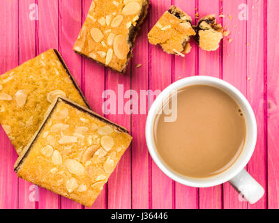 Cherry Bakewell Tarts With a Cup or Mug of Tea or Coffee Against a Pink Background Stock Photo