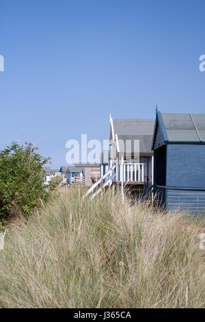 UK Norfolk coastline, beach huts sitting among the stand dunes at Old Hunstanton beach, blue sky, sunny day at the beach, coast Stock Photo