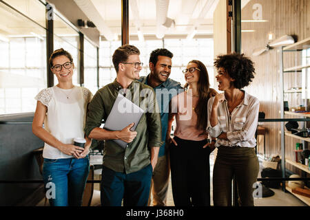 Portrait of successful business team standing together and smiling. Multi ethnic business people at startup. Stock Photo
