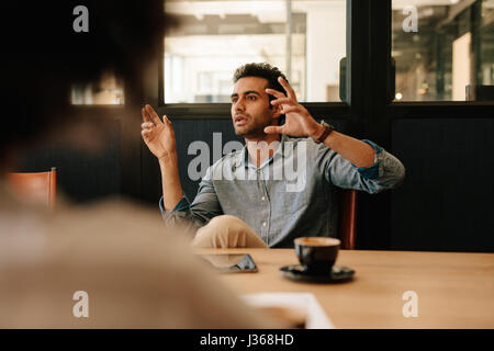 Shot of young man explaining business strategy to colleagues in conference room. Businessman talking with coworkers during office meeting.