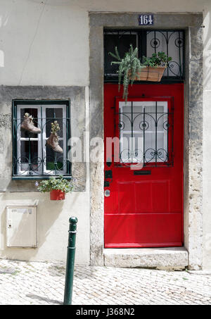 Front doors of two adjoining houses, numbers 164 & 166, one red one green, with a small window between them with two boots acting as planters. Stock Photo