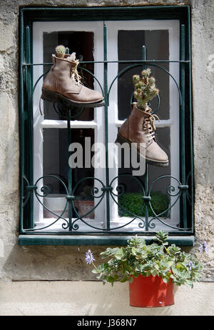 Front doors of two adjoining houses, numbers 164 & 166, one red one green, with a small window between them with two boots acting as planters. Stock Photo