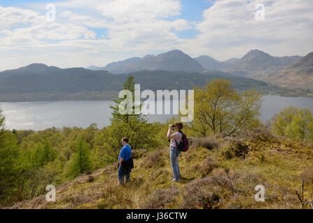 A couple gaze over Loch Lomond from a hilltop near Inversnaid, Scotland, UK Stock Photo