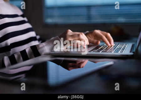 Unrecognizable woman sitting at desk working on laptop. Stock Photo