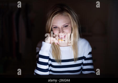 Woman in striped sweater holding pencil sitting at desk Stock Photo