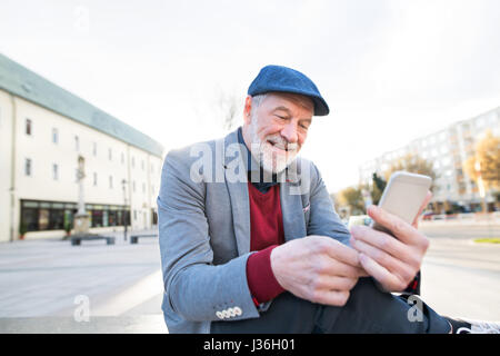 Senior man in town with smart phone, texting