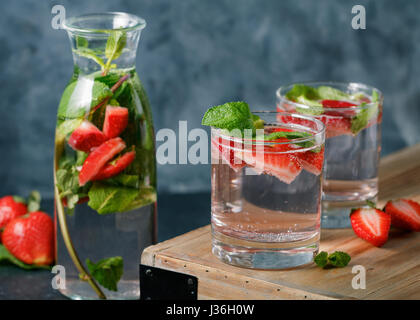 Detox water with fresh mint and strawberries in transparent glasses against the blue wall Stock Photo